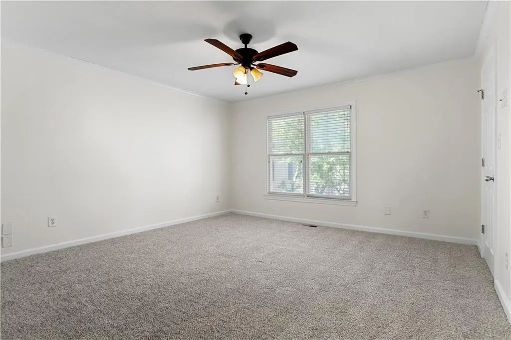 Empty room featuring carpet, crown molding, and ceiling fan
