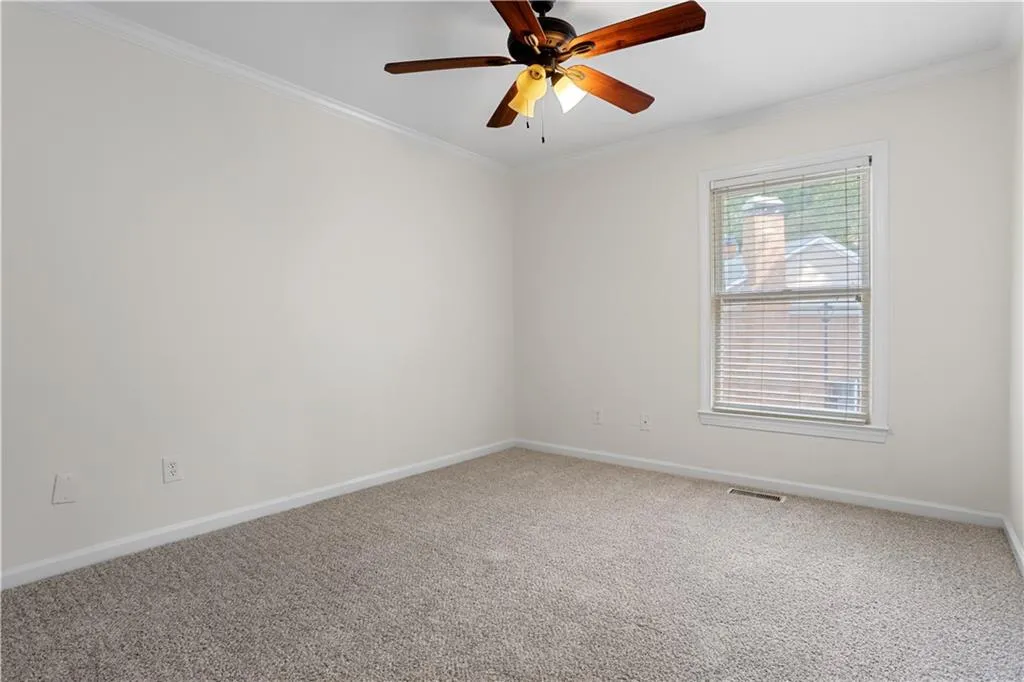 Empty room featuring crown molding, carpet, and ceiling fan