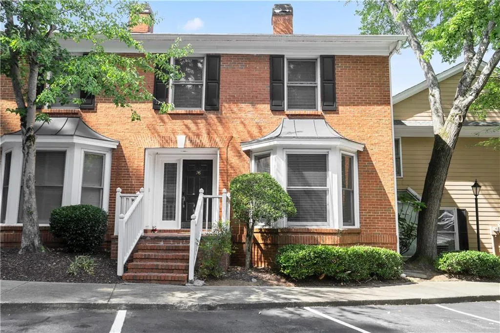 View of front of home featuring brick siding, a chimney, and uncovered parking
