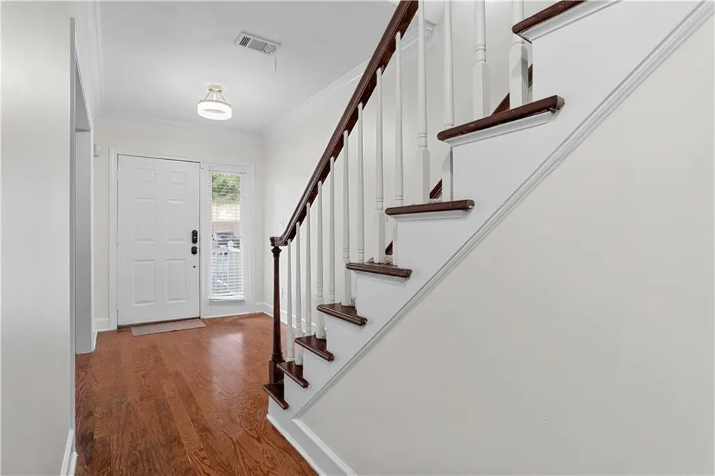 Entryway featuring crown molding, wood finished floors, and stairs