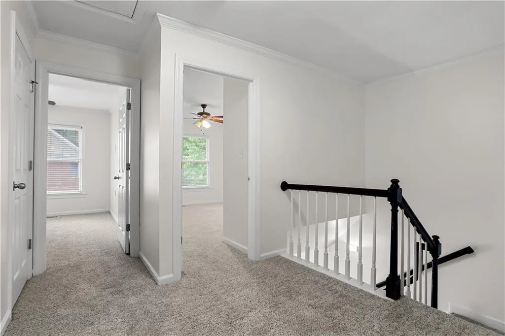 Hall with ornamental molding, light carpet, and an upstairs landing