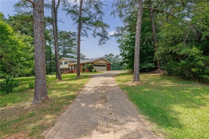 Brick paver driveway leading to a traditional home with a two-car garage