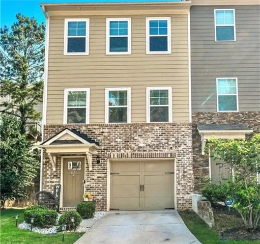 Three-story exterior featuring tan horizontal siding and brick accents