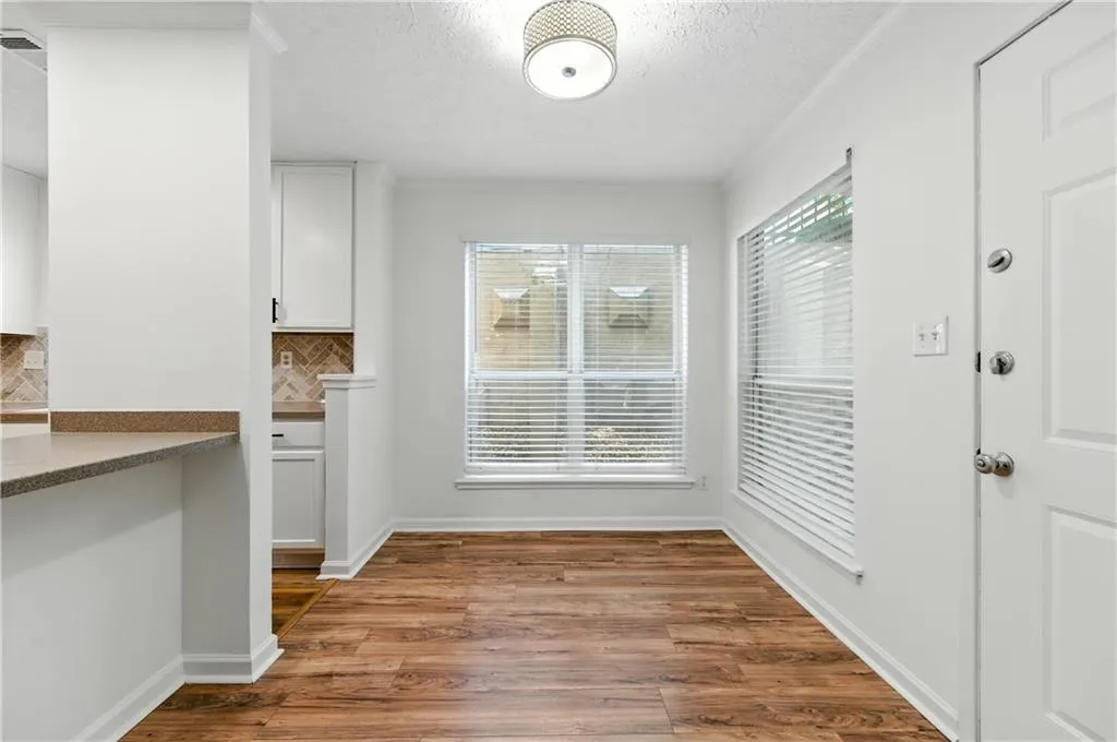 Unfurnished dining area featuring healthy amount of natural light, wood finished floors, a textured ceiling, and crown molding