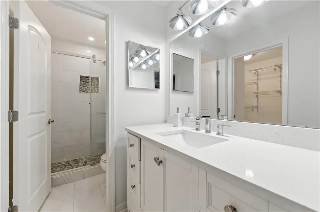 Bathroom featuring a stall shower, vanity, a walk in closet, and marble finish floors