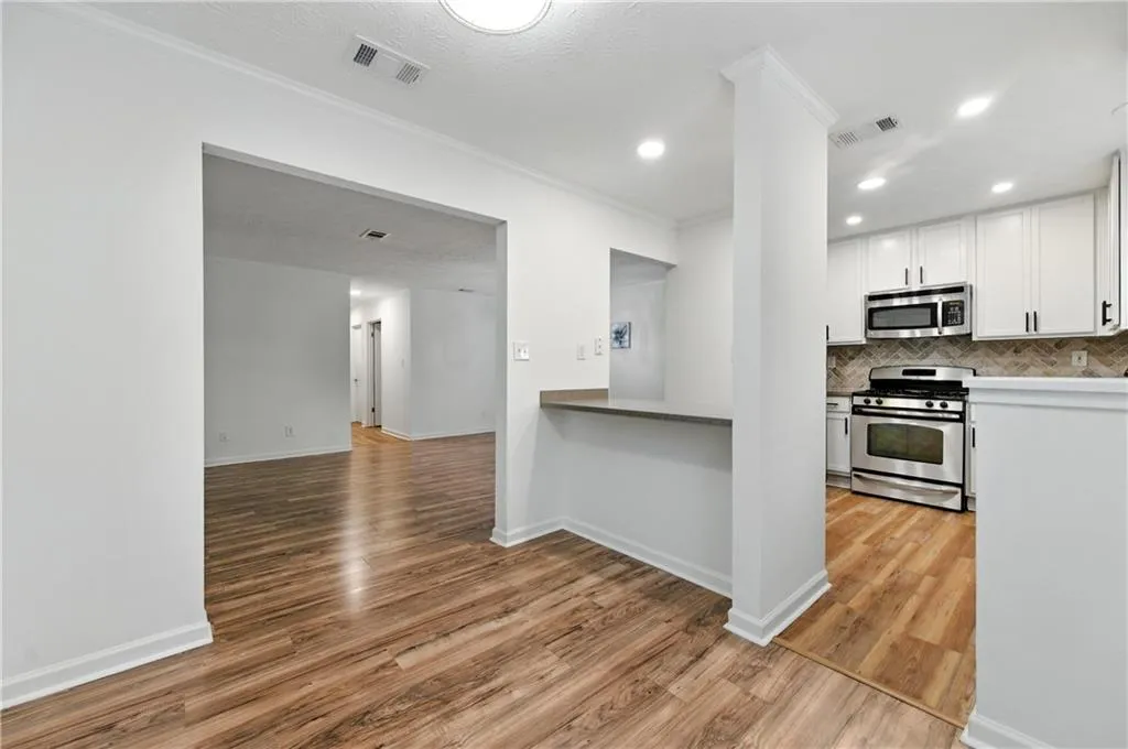 Kitchen featuring appliances with stainless steel finishes, light wood-type flooring, recessed lighting, white cabinetry, and decorative backsplash