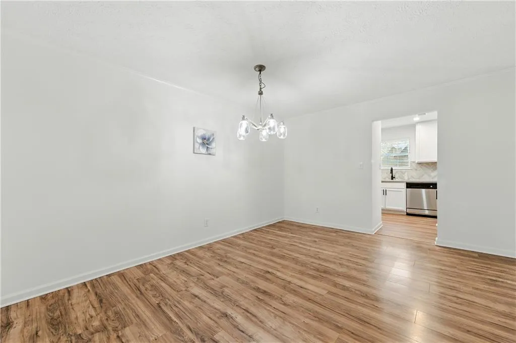 Unfurnished dining area featuring light wood finished floors, a chandelier, and a textured ceiling