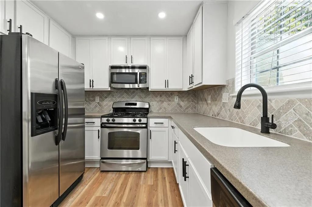 Kitchen featuring stainless steel appliances, white cabinets, light wood finished floors, tasteful backsplash, and recessed lighting