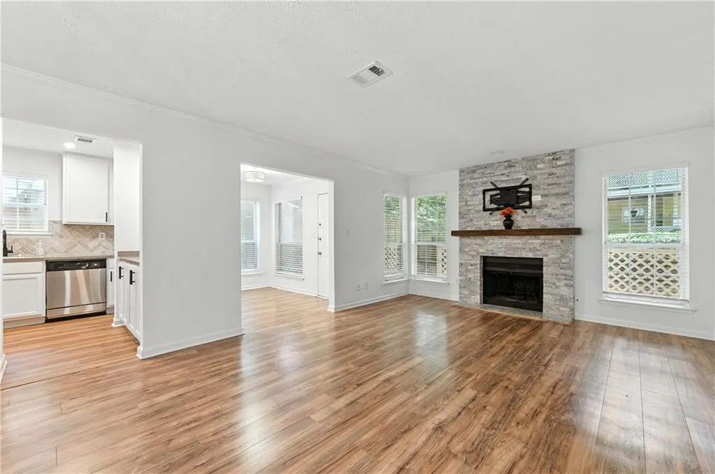 Unfurnished living room with a fireplace, crown molding, light wood-style floors, and a textured ceiling