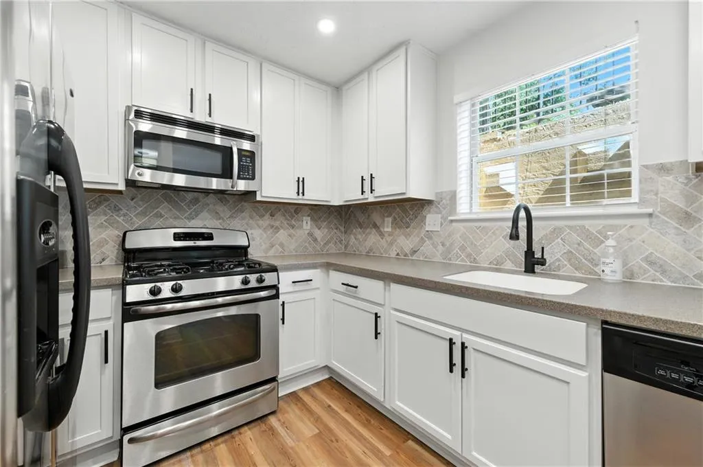Kitchen featuring appliances with stainless steel finishes, light wood-style floors, white cabinetry, decorative backsplash, and recessed lighting