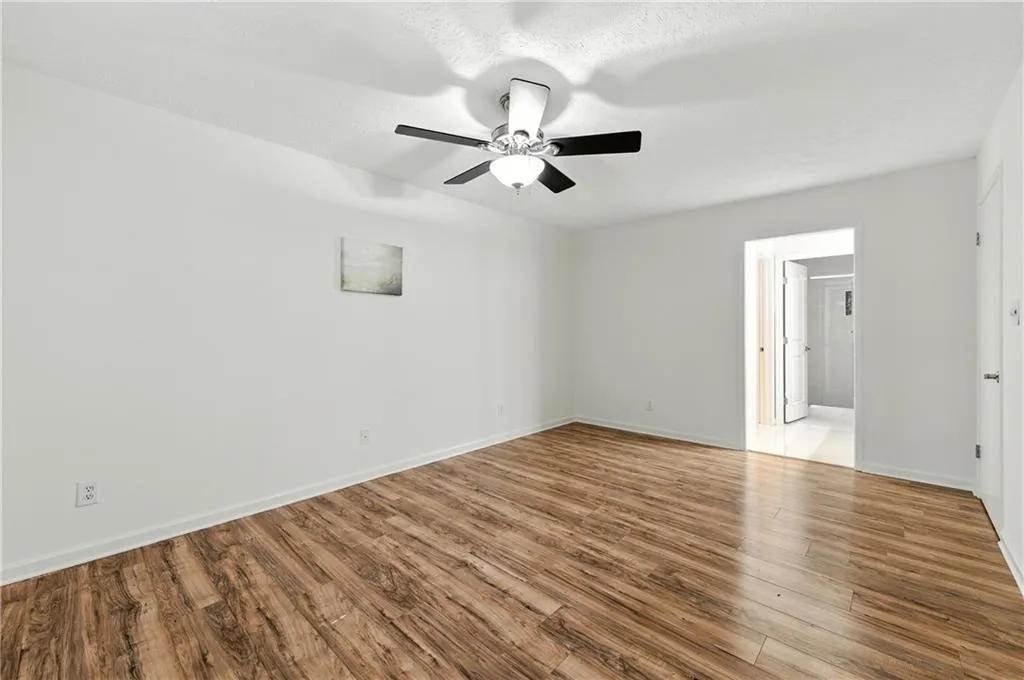 Unfurnished bedroom featuring wood finished floors, ceiling fan, and ensuite bathroom