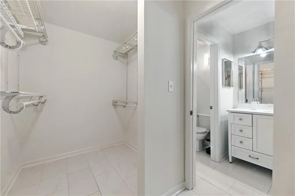 Walk in closet featuring light marble finish flooring