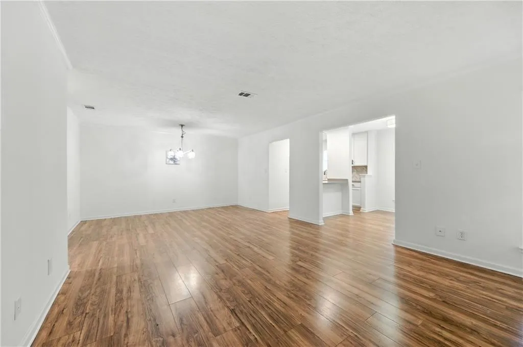 Unfurnished living room featuring wood finished floors and a chandelier