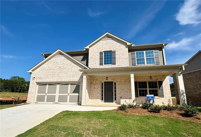 Brick exterior with an inviting covered porch, two-car garage, and upper-level windows with shutters