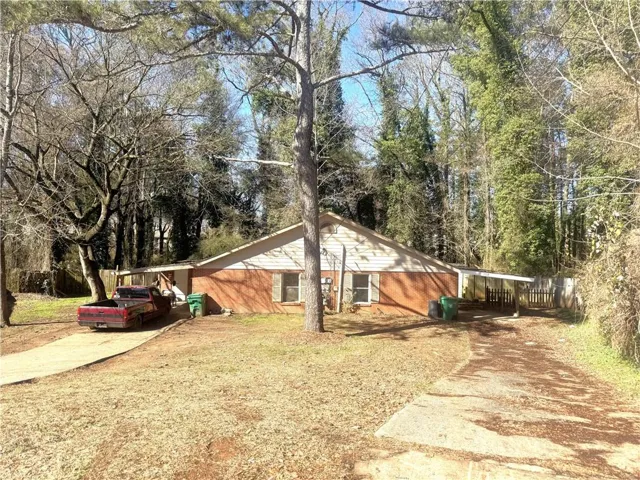 View of side of property with concrete driveway and view of scattered trees