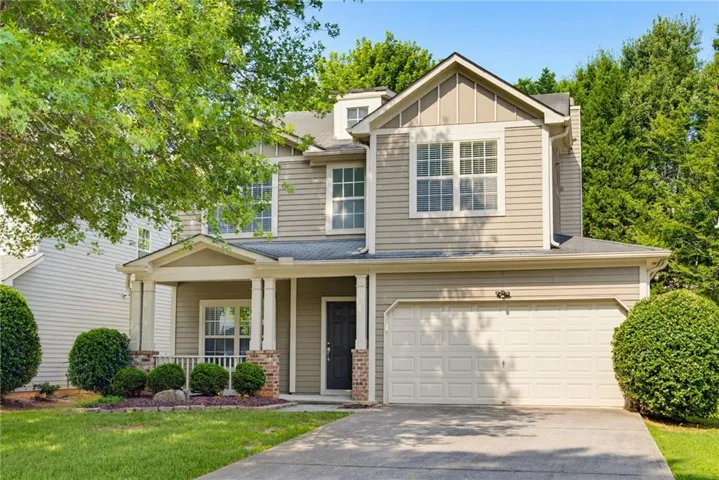 Contemporary two-story residence featuring light beige siding and a covered front porch