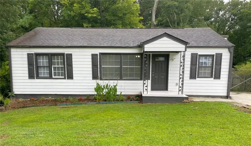 View of front of home featuring view of scattered trees and roof with shingles