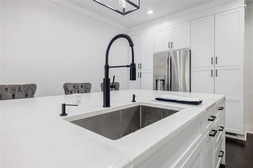 Details with white cabinetry, stainless steel refrigerator with ice dispenser, crown molding, a sink, and light stone counters