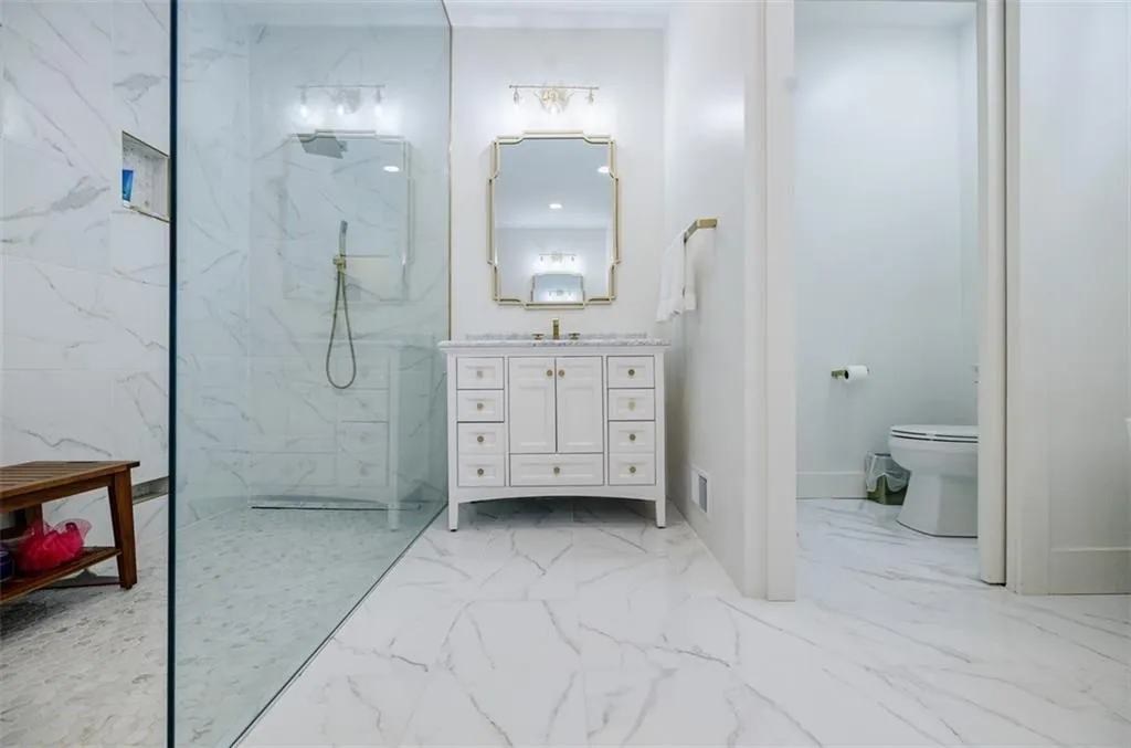 Bathroom with vanity, a marble finish shower, toilet, marble finish floor, and visible vents