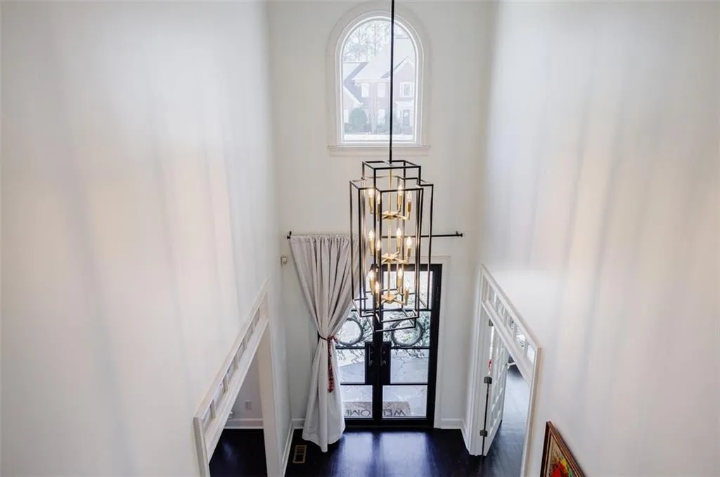 Stairs with wood finished floors, a towering ceiling, and a chandelier