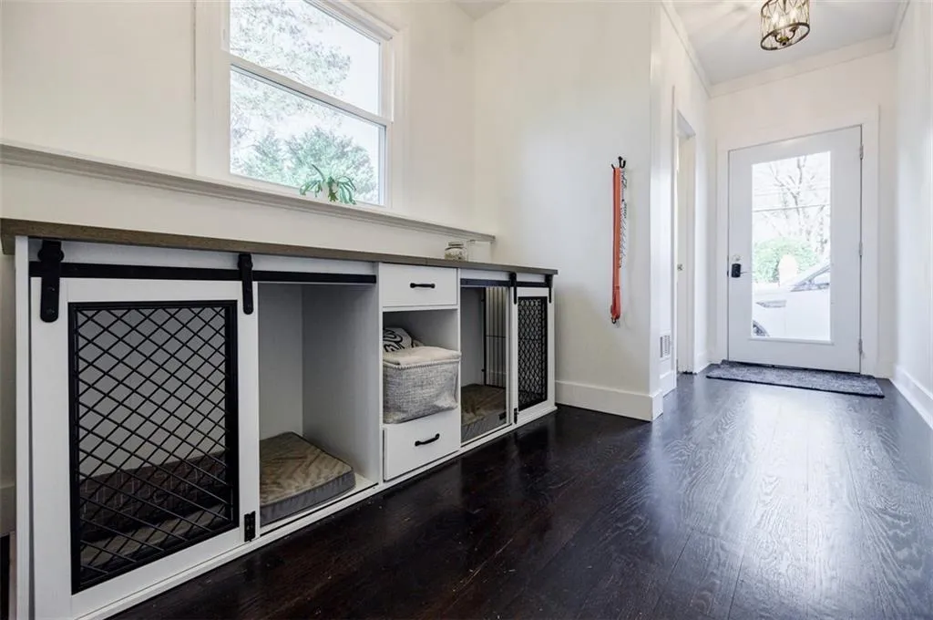 Entryway with dark wood-type flooring, baseboards, and crown molding