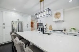 Kitchen featuring a sink, pendant lighting, a breakfast bar, stainless steel fridge, and white cabinets