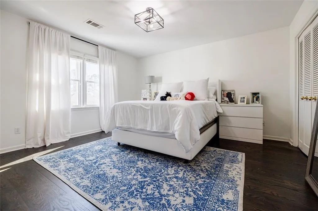 Bedroom with baseboards, dark wood-style flooring, and visible vents