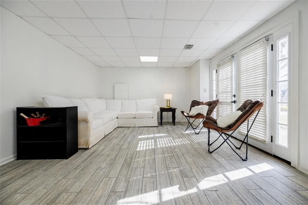 Living area with a paneled ceiling, baseboards, light wood-style floors, and visible vents