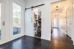 Entryway with a barn door, baseboards, crown molding, and dark wood-style flooring