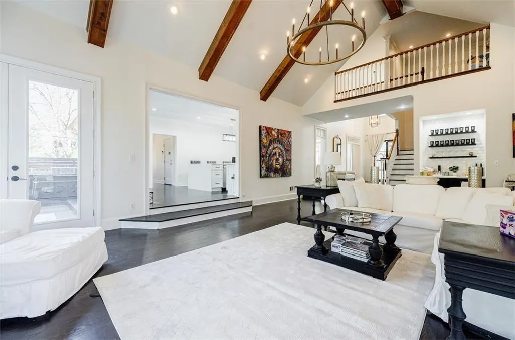 Living area featuring dark wood finished floors, a notable chandelier, high vaulted ceiling, and stairway