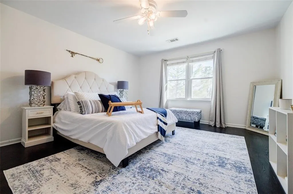 Bedroom with dark wood-style floors, baseboards, and visible vents