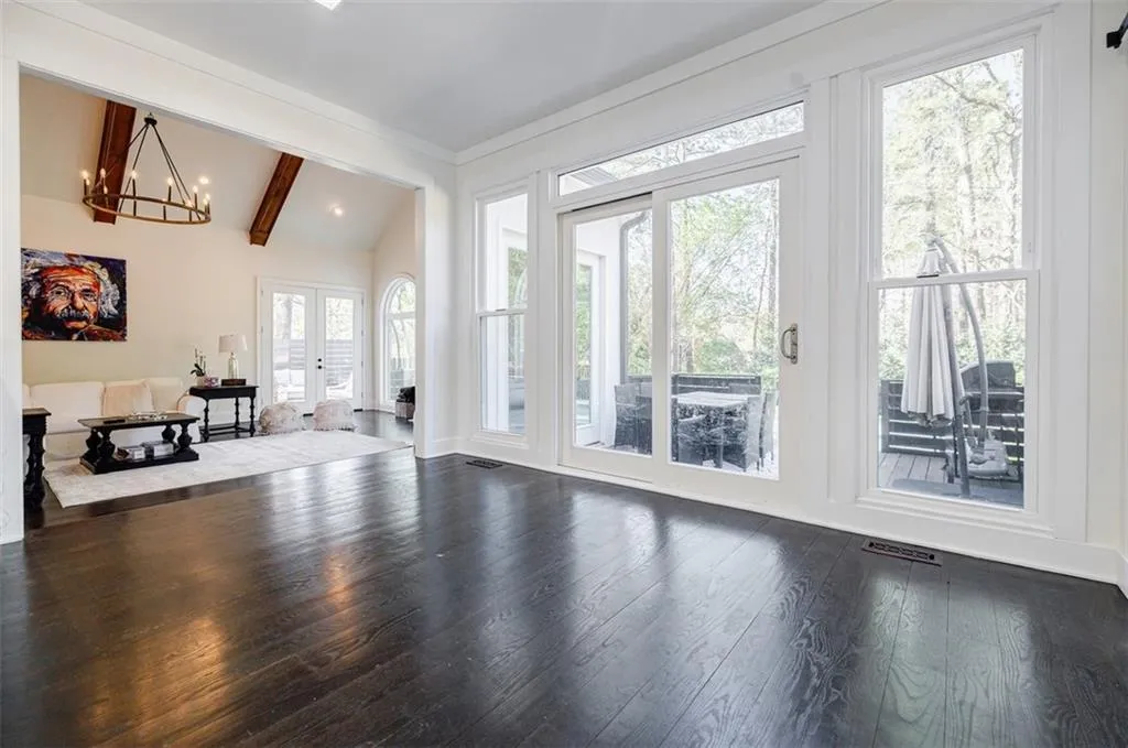 Unfurnished living room featuring dark wood-style floors, visible vents, vaulted ceiling with beams, and an inviting chandelier