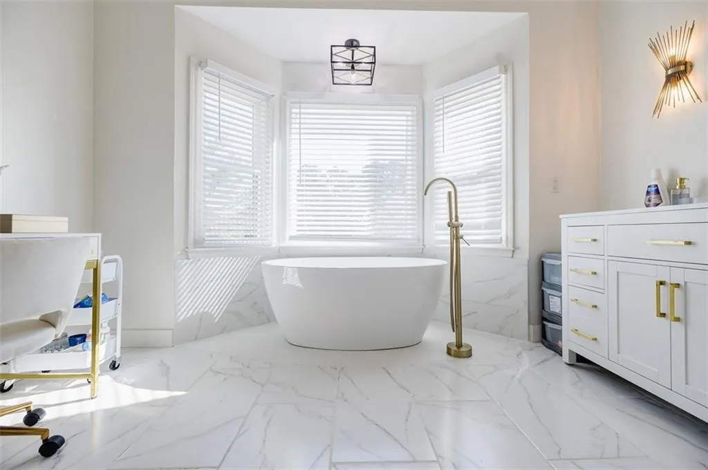 Bathroom with marble finish floor, a freestanding tub, and plenty of natural light