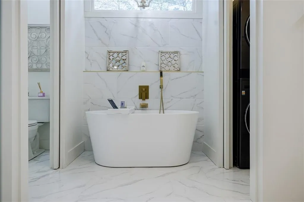 Full bath featuring marble finish floor, toilet, and a freestanding tub