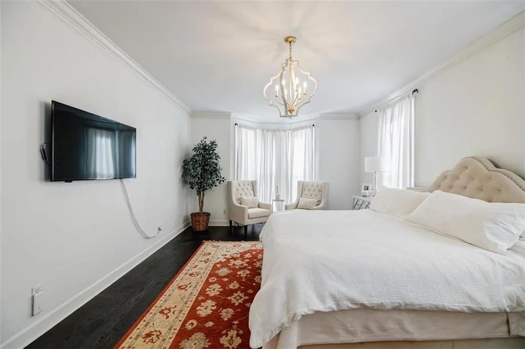 Bedroom with ornamental molding, dark wood-style floors, baseboards, and a chandelier