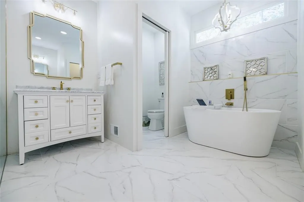 Full bathroom with visible vents, marble finish floor, toilet, vanity, and a freestanding bath