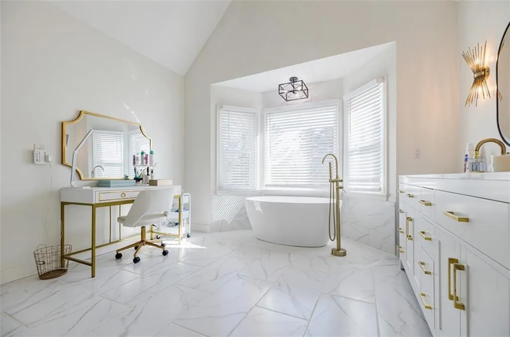 Full bathroom with marble finish floor, vanity, high vaulted ceiling, and a freestanding bath