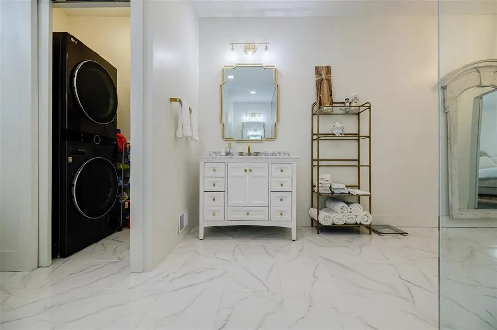 Bathroom featuring marble finish floor, visible vents, stacked washer / dryer, and vanity
