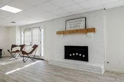 Living room with a drop ceiling, a fireplace, and wood finished floors