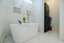 Bathroom with a soaking tub and marble finish floor