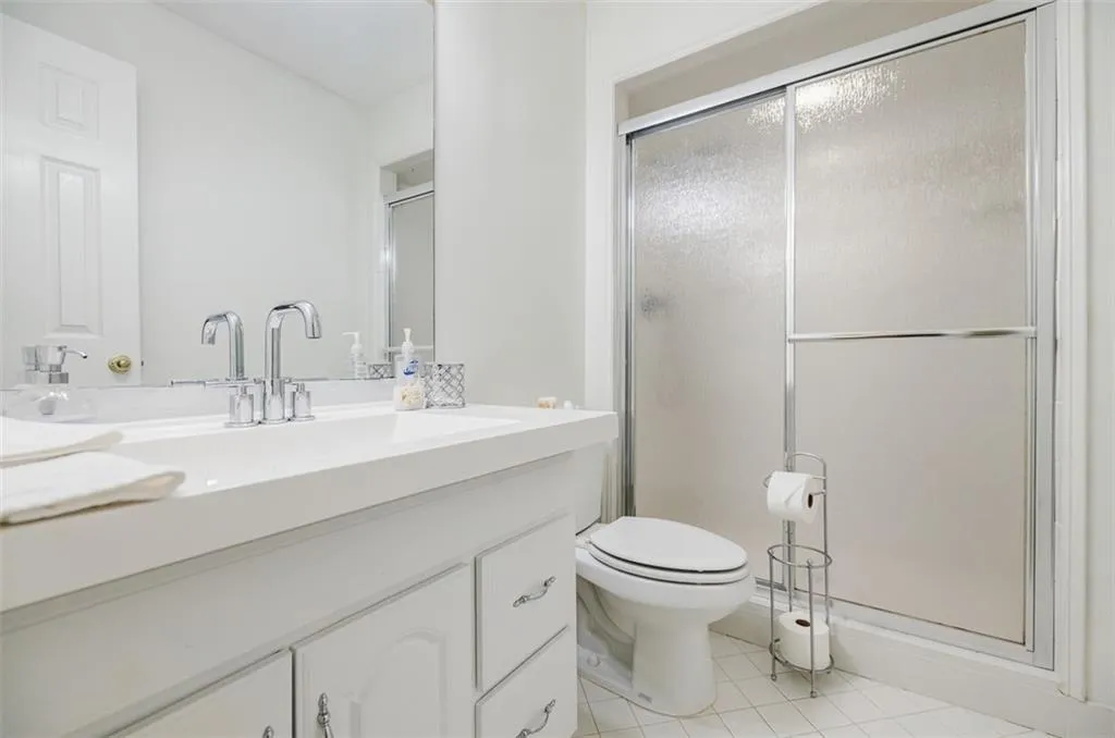 Full bathroom with toilet, vanity, a stall shower, and tile patterned flooring