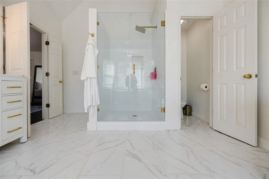 Ensuite bathroom featuring marble finish floor, baseboards, toilet, and a shower stall
