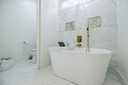 Full bathroom featuring marble finish floor and a freestanding bath