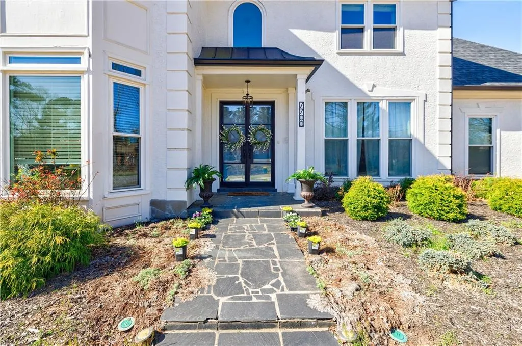 Doorway to property with metal roof, a standing seam roof, stucco siding, a shingled roof, and french doors