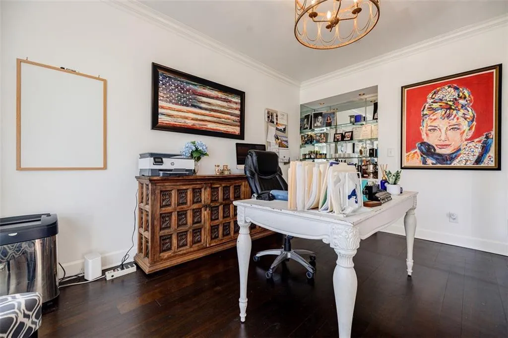 Office space with ornamental molding, baseboards, a notable chandelier, and wood finished floors