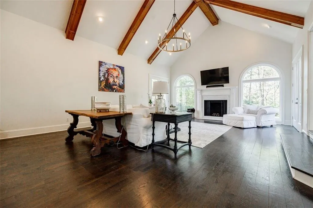 Living area featuring high vaulted ceiling, beamed ceiling, hardwood / wood-style flooring, a fireplace, and a notable chandelier