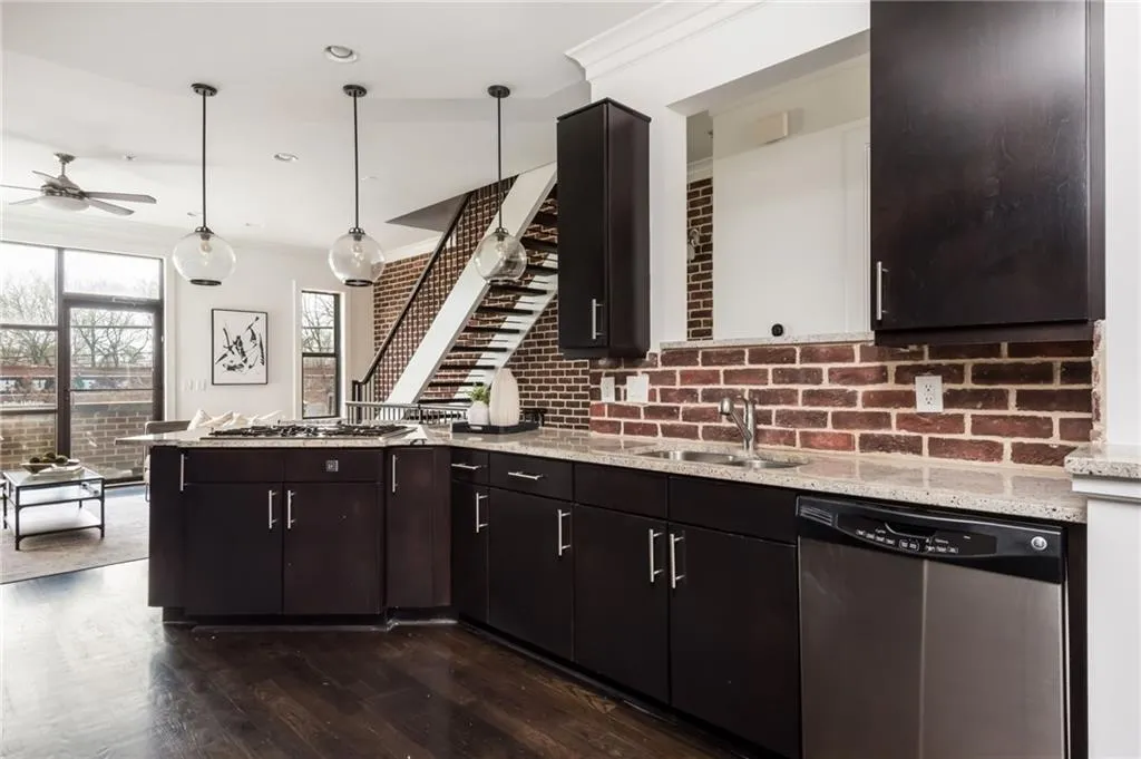 Large kitchen features brick backsplash, hardwood floors, stainless steel appliances and updated light fixtures.