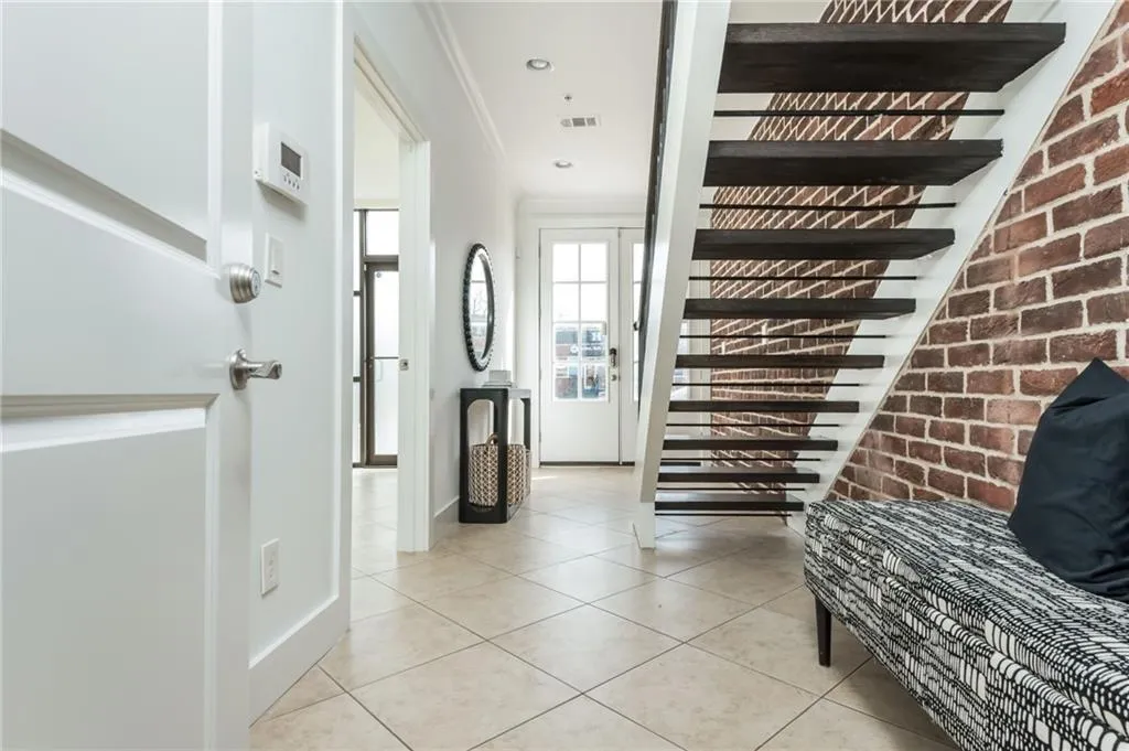 Grand entrance foyer with floating staircase and brick accent wall gives modern, urban character