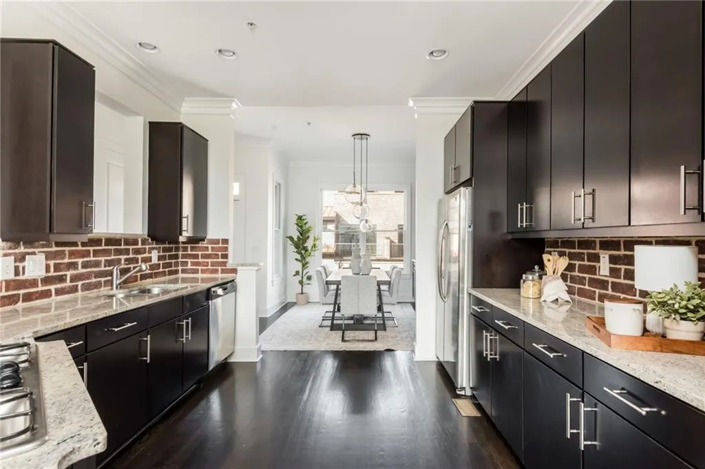 Large kitchen features brick backsplash, hardwood floors, stainless steel appliances and updated light fixtures.