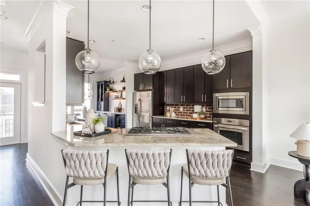 Large kitchen features brick backsplash, hardwood floors, stainless steel appliances and updated light fixtures.